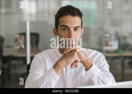Focused young businessman sitting alone in a modern office Stock Photo