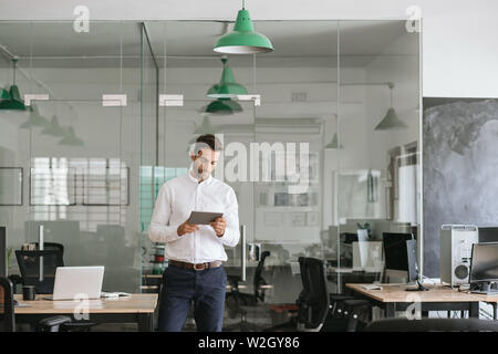 Young businessman using a tablet while standing in an office Stock Photo