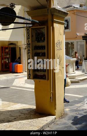 Corfu town scene central in a square with shops around not many people a central pillar with a sign on is the main point of interset Stock Photo
