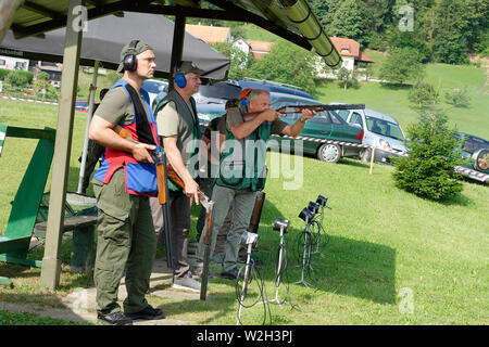 Trapshooting. Competitors shooting shotguns at clay targets. Stock Photo