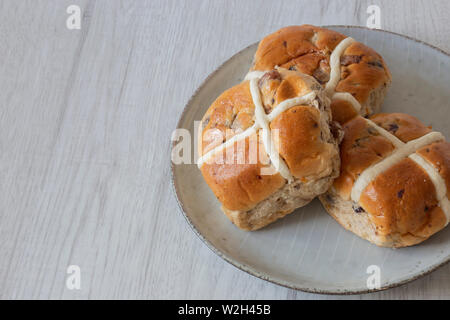 Hot cross buns piled on a green glazed plate with a grey wood background Stock Photo