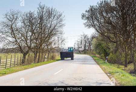 Excavator moves on asphalt road in spring Stock Photo