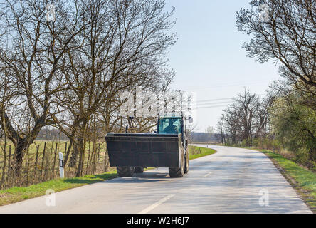 Excavator moves on asphalt road in spring Stock Photo