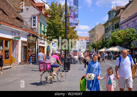 Sibiu, Romania .  Food Panda, a food delivery service, cyclist cycling cobblestone city street to deliver an order for a customer. Stock Photo