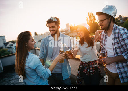 Young people partying on terrace with drinks at sunset Stock Photo