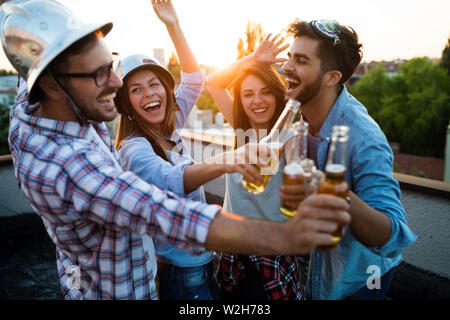 Young people partying on terrace with drinks at sunset Stock Photo