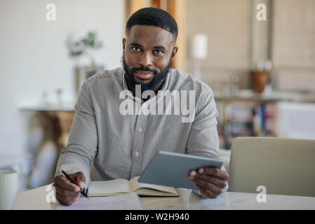 Smiling African American man using a digital tablet at home Stock Photo