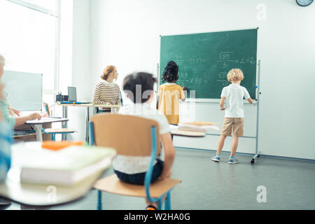 Two classmates writing together on the blackboard. Stock Photo