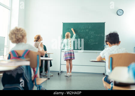 School girl speaking and writing in front of the class. Stock Photo