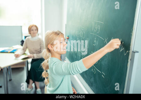 Happy girl doing sums near the school board. Stock Photo