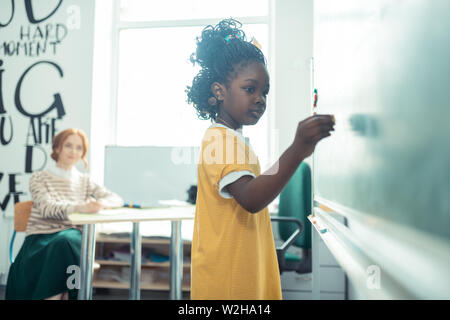 Thoughtful girl going to write on a blackboard. Stock Photo