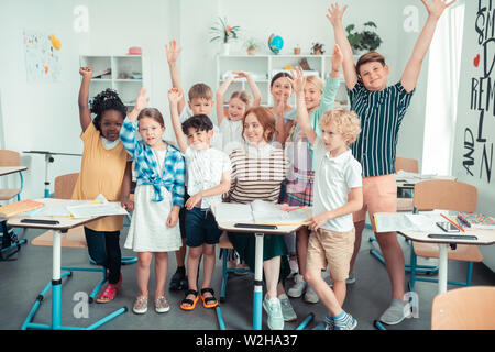 Elementary school class standing around their teacher. Stock Photo