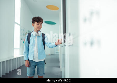 Schoolboy opening his school locker during school break Stock Photo