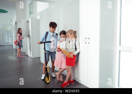 Boy and girls standing near lockers while having break from lesson Stock Photo