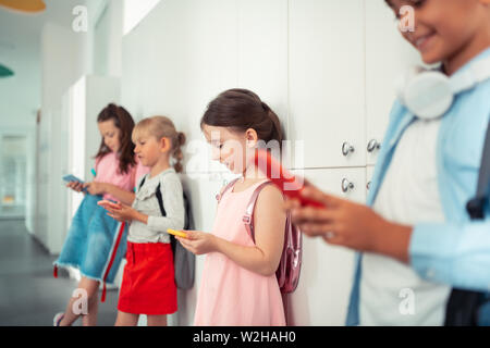 Boys and girls addicted to gadgets playing games on phones Stock Photo