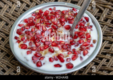 Metal bowl with muesli and yogurt with banana, apple, pomegranate seeds and oat cereals, healthy food concept, close up Stock Photo