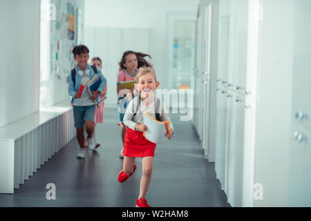 Happy girl wearing red skirt running home from school Stock Photo