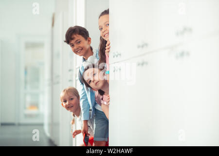 Boy and girls smiling while standing near lockers at school break Stock Photo