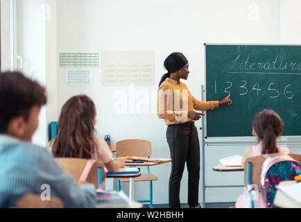 Dark-haired teacher standing near the blackboard Stock Photo