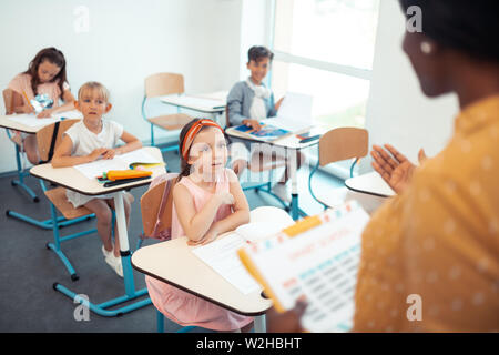 Attentive smart pupils listening to their professional teacher Stock Photo
