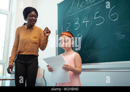 Cute dark-haired girl answering near the blackboard Stock Photo