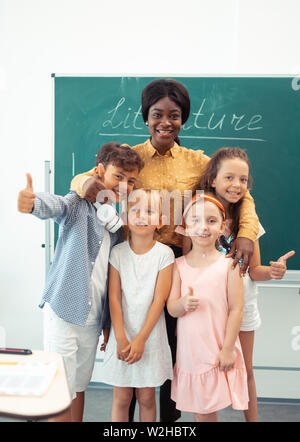 Children feeling truly happy standing near their kind loving teacher Stock Photo