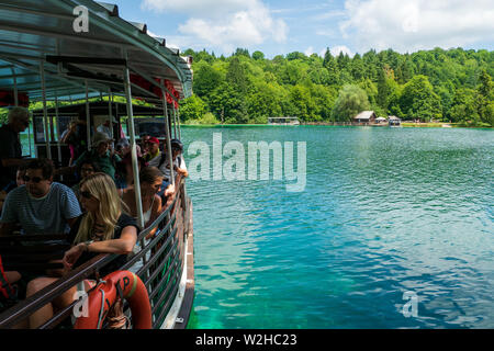 Ferry navigating on the turquoise colored crystal clear and pure water of Lake Kozjak, Plitvice Lakes National Park, Croatia Stock Photo