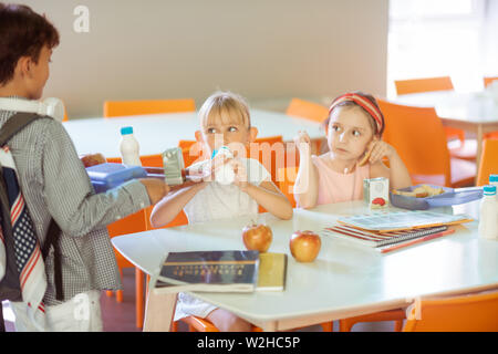 Dark-haired boy joining classmates in the school canteen Stock Photo