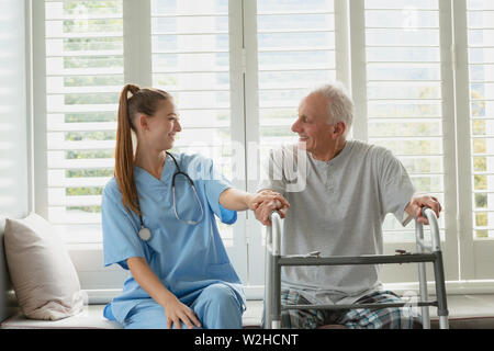Female doctor consoling active senior man on window seat Stock Photo