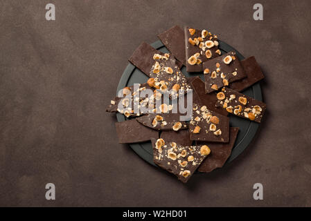 hazelnut dark chocolate pieces on black plate Stock Photo