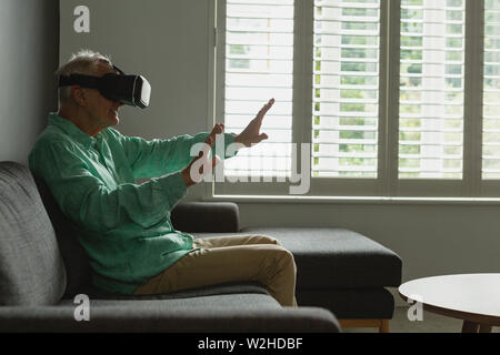 Active senior man using virtual reality headset in living room Stock Photo