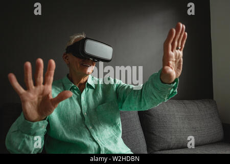 Active senior man using virtual reality headset in living room Stock Photo