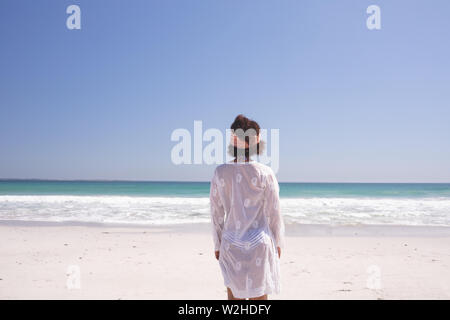 Rear view of woman standing on the beach Stock Photo
