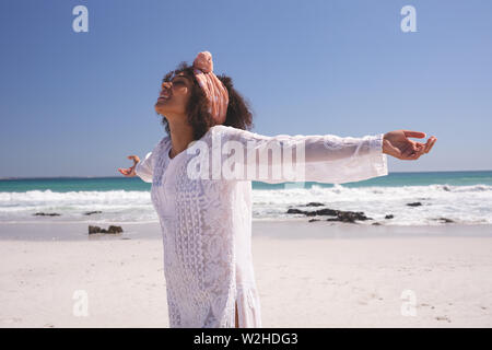 Beautiful woman with arms stretched out standing on the beach Stock Photo