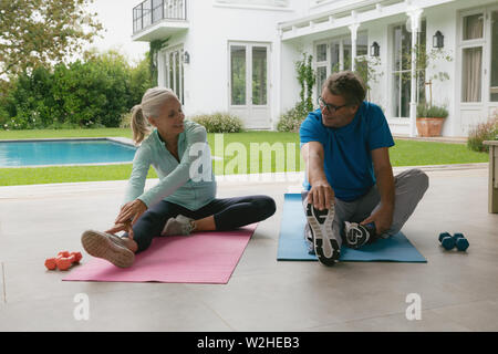 Active senior couple doing stretching exercise in the porch at home Stock Photo