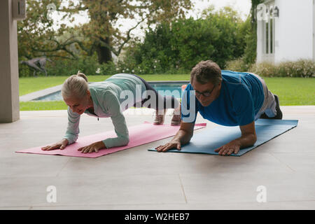 Active senior couple doing plank exercise in the porch at home Stock Photo