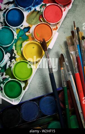 Box of watercolors and brushes on a table. Stock Photo