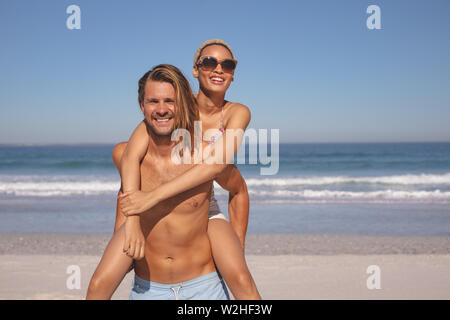 Man giving piggyback ride to woman on the beach Stock Photo