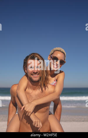 Man giving piggyback ride to woman on the beach Stock Photo