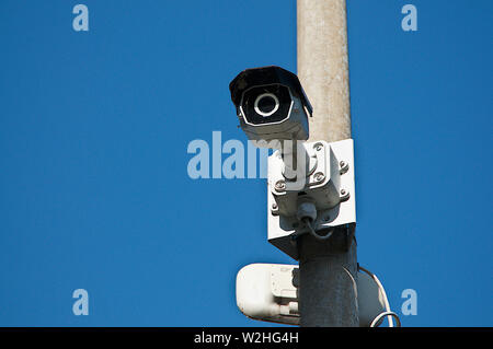 Close up picture of a CCTV surveillance security camera video installed on a street light pole with a blue sky in the background and located in Caslan Stock Photo