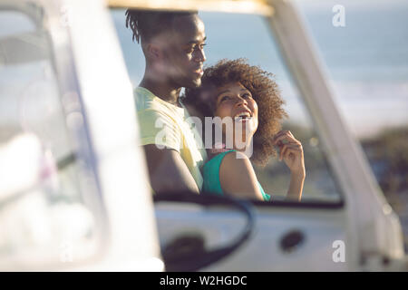 Man embracing woman near camper van at beach Stock Photo