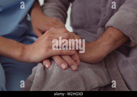 Female doctor consoling active senior man in a comfortable home Stock Photo