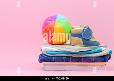 Donation concept. Kid toys, books and clothes for donate or charity on pink background Stock Photo