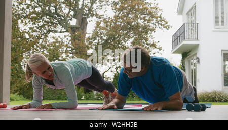 Active senior couple doing plank exercise in the porch at home Stock Photo