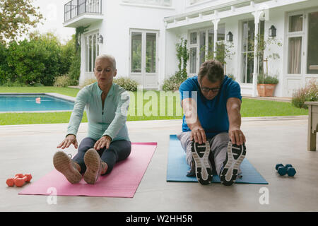 Active senior couple doing stretching exercise in the porch at home Stock Photo