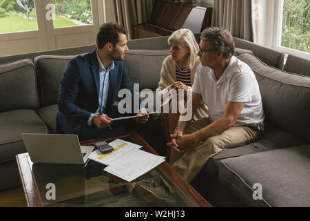 Active senior couple discussing with real estate agent in living room Stock Photo
