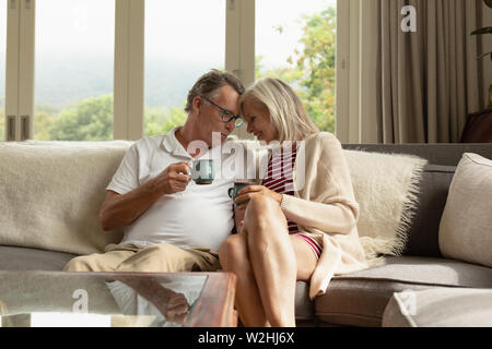 Romantic active senior couple having coffee on sofa in a comfortable home Stock Photo