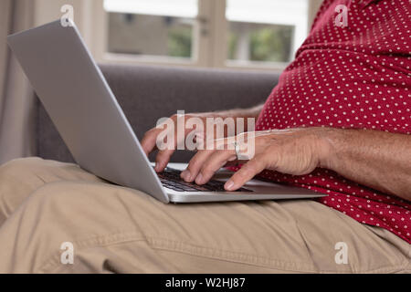 Active senior man using laptop on sofa in a comfortable home Stock Photo