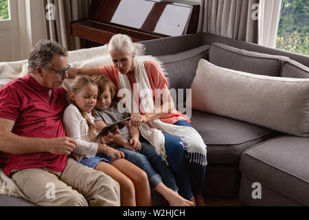 Multi-generation family using digital tablet on sofa in a comfortable home Stock Photo
