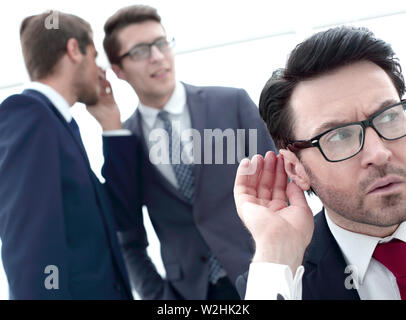 close up.businessman eavesdropping on conversation between colleagues Stock Photo